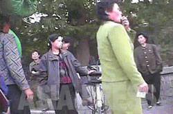 スカート姿の女性同盟の糾察隊員が、盛んに笛を吹きながら服装取締りをしている。自転車に乗っていていたり、ズボンをはいてるという理由で取締りに遭った人たちが一箇所に集められている。 （2008年10月沙里院市　シム・ウィチョン撮影）